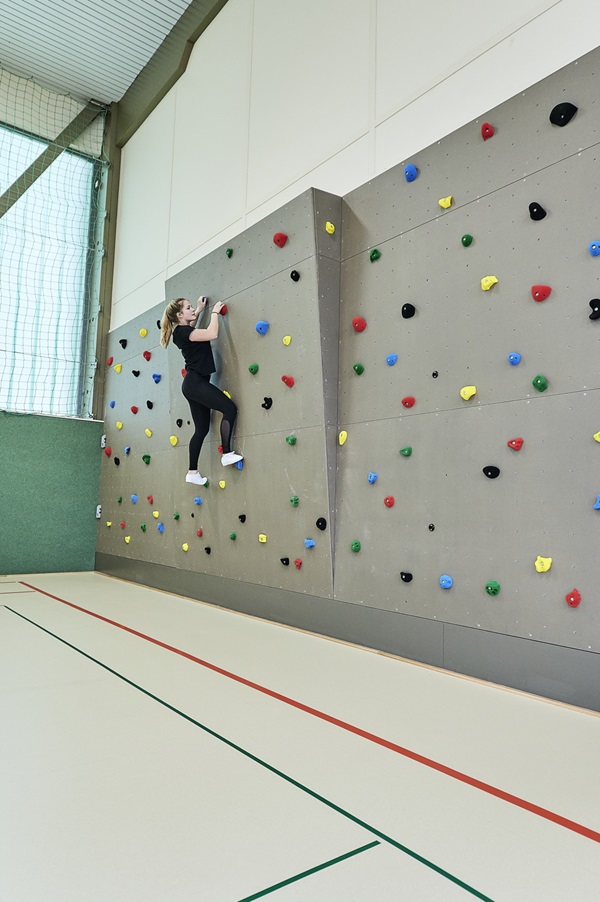 Kletterwand in einer Turnhalle, junge Frau beim Klettern
