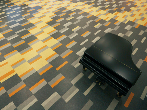 Rubber planks laid in a pattern in a school auditorium. Detail from the motif showing a winged snake