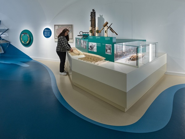 Museum, Thema Schiffsbau - historische Ausstellungsstücke, Miniatur-Nachbau und Fotos. Eine Jugendliche mit einem Holz-Modell zum Anfassen